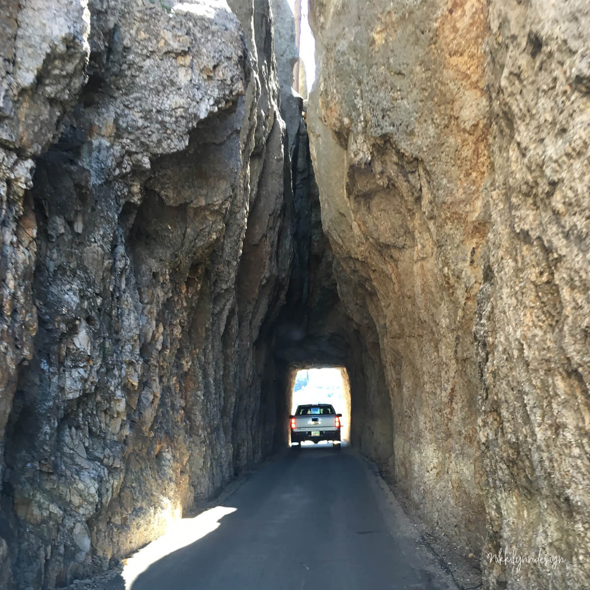 Driving through a narrow rock tunnel on Needles Highway in Custer State Park, South Dakota