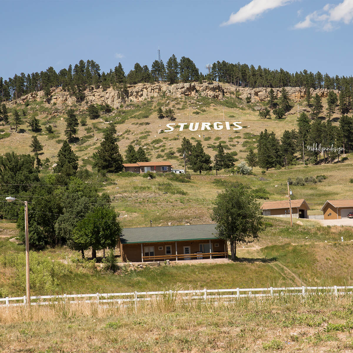 Sturgis sign on a hillside above homes and grassy slopes in Sturgis, South Dakota