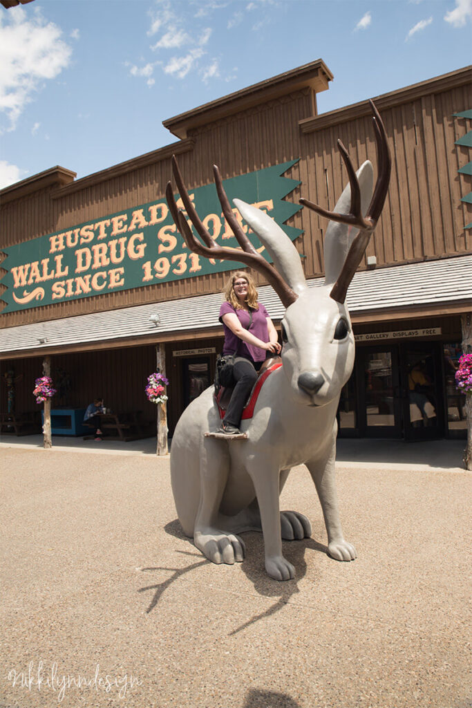 Person sitting on the giant jackalope statue outside Wall Drug Store in Wall South Dakota