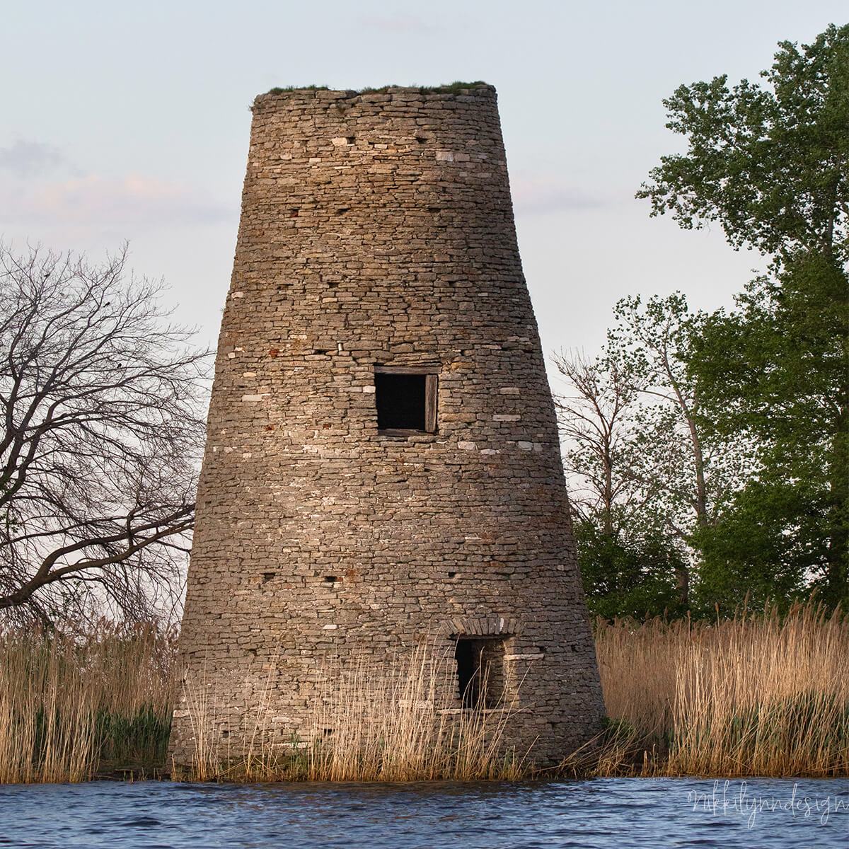 Longtail Point Lighthouse ruins in Green Bay Wisconsin standing beside marsh grasses and shallow water.
