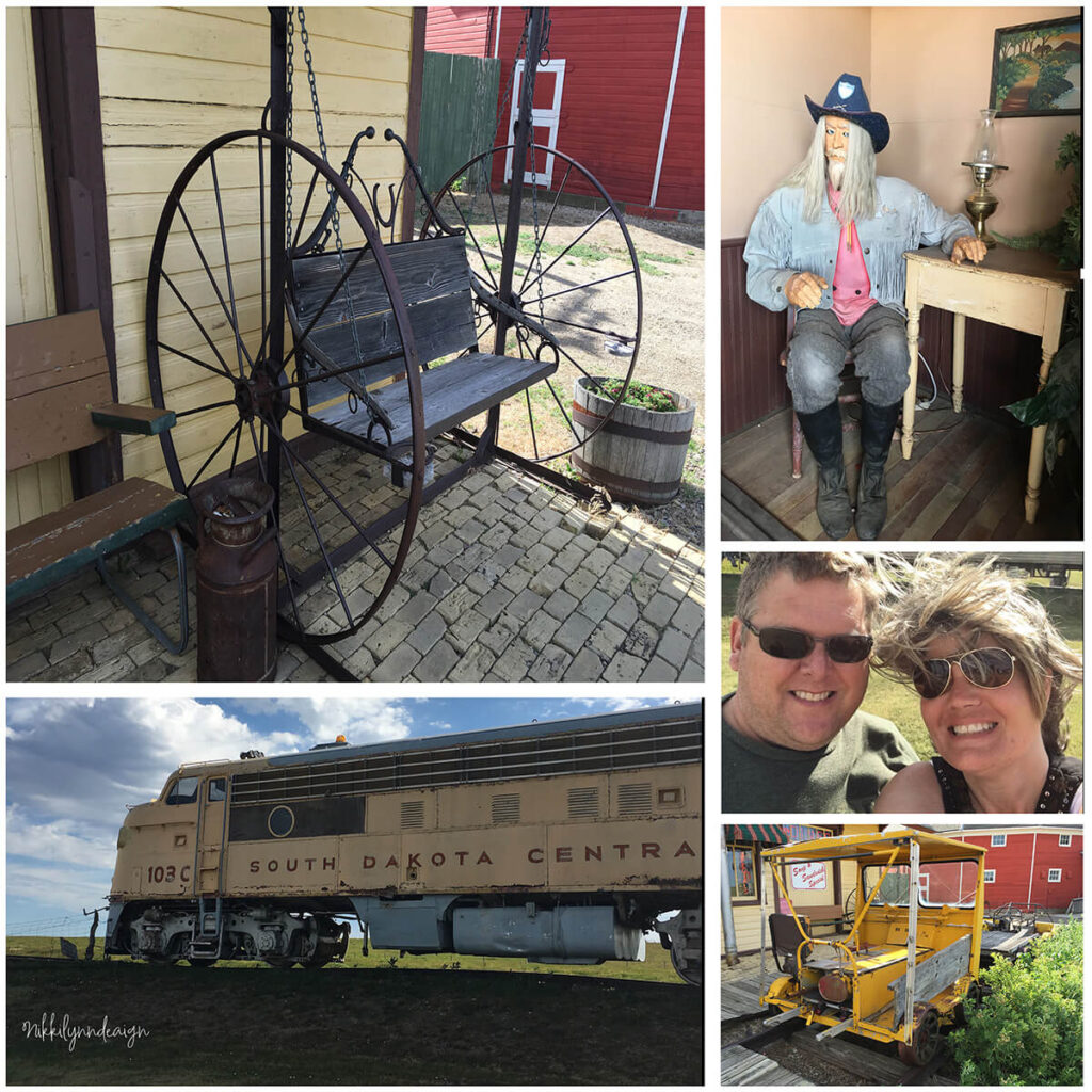 Historic displays at 1880 Town in South Dakota including antique railroad engine, old west wagon bench, vintage rail cart, cowboy figure, and visitors exploring the frontier museum.