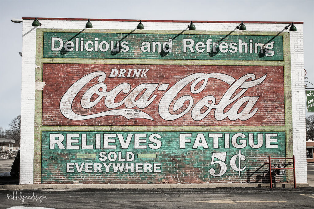 Historic Coca-Cola painted brick wall advertising mural reading Delicious and Refreshing Drink Coca-Cola Relieves Fatigue Sold Everywhere 5 cents