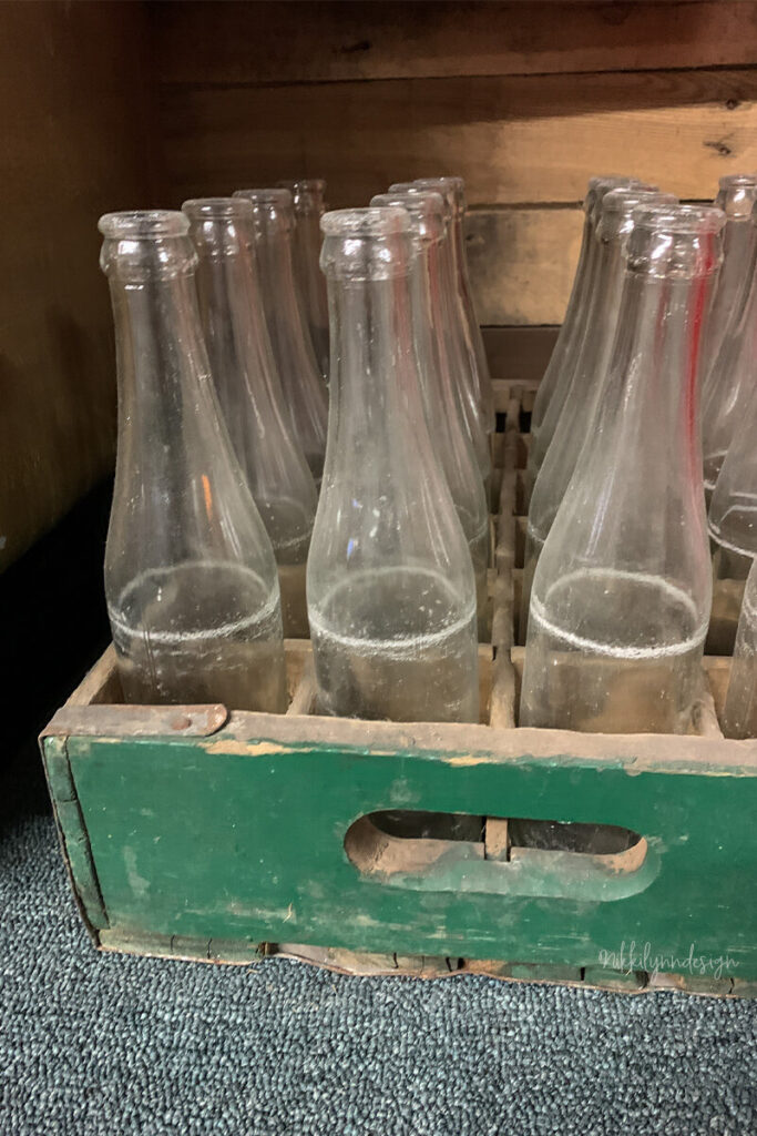 Vintage glass soda bottles stored in a green wooden beverage crate